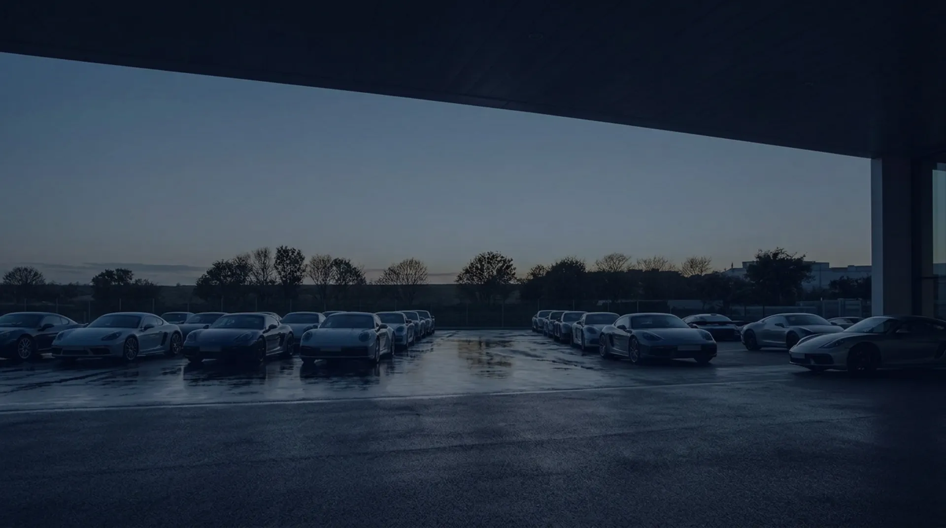 Rows of sports cars parked at a dealership lot at dusk
